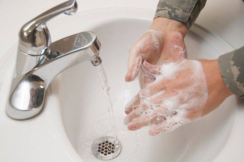 Моет руки в раковине